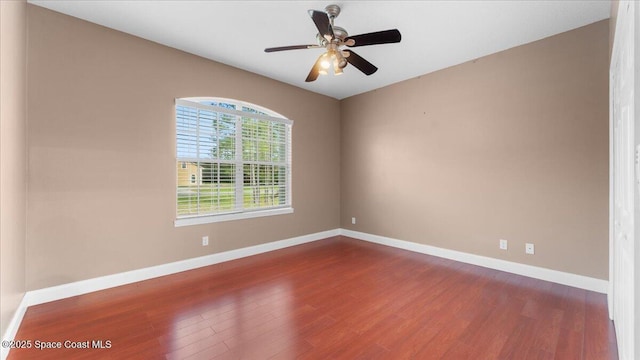 spare room featuring dark wood-style floors, baseboards, and a ceiling fan