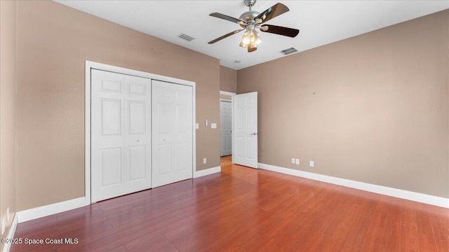 unfurnished bedroom with a closet, wood finished floors, and visible vents