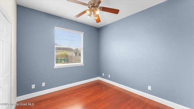 unfurnished room featuring dark wood-style floors, a ceiling fan, and baseboards