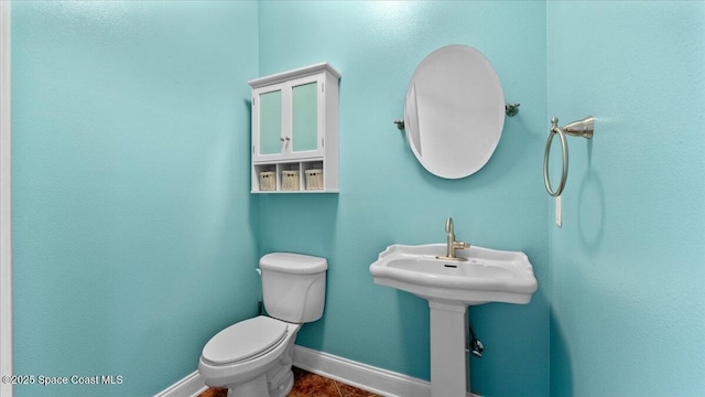 bathroom with a sink, toilet, and baseboards