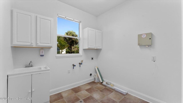 clothes washing area featuring baseboards, cabinet space, hookup for an electric dryer, and a sink