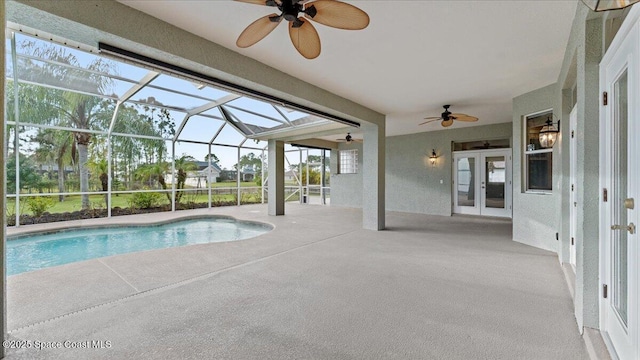 pool with french doors, a patio area, a lanai, and a ceiling fan