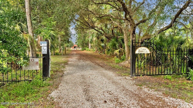 view of road featuring driveway and a gate