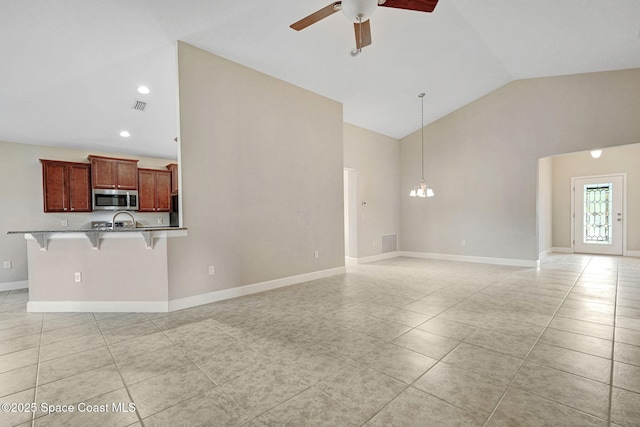 unfurnished living room featuring high vaulted ceiling, ceiling fan with notable chandelier, and light tile patterned floors