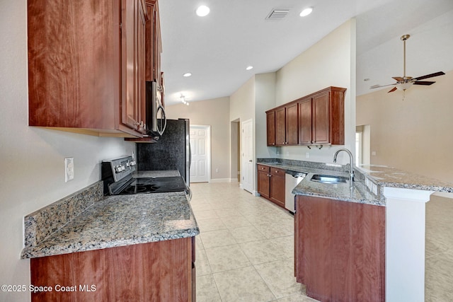 kitchen featuring sink, vaulted ceiling, dark stone countertops, appliances with stainless steel finishes, and kitchen peninsula