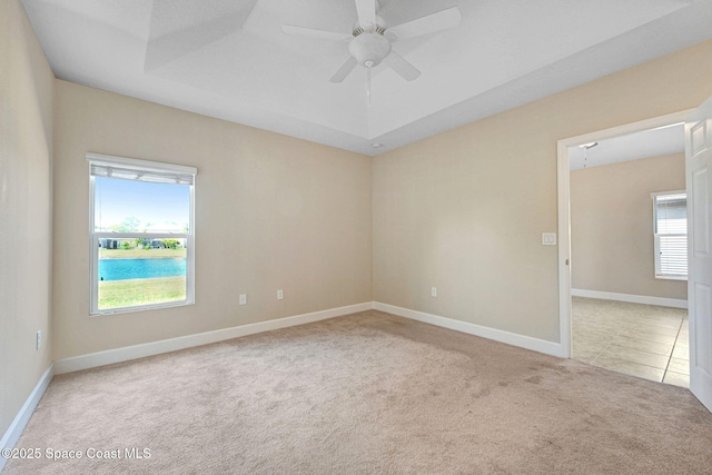 carpeted empty room featuring a tray ceiling and ceiling fan