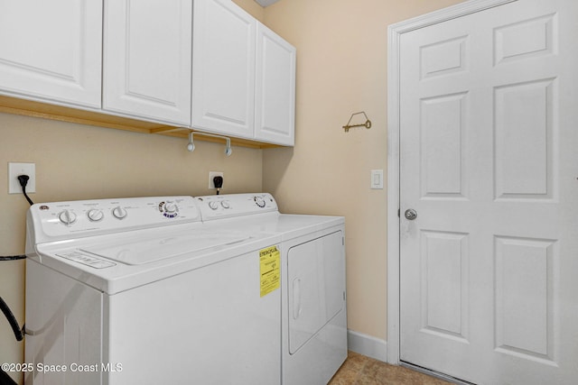 clothes washing area with washer and dryer and cabinets