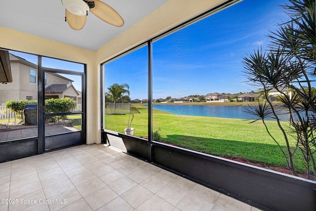 unfurnished sunroom featuring ceiling fan and a water view