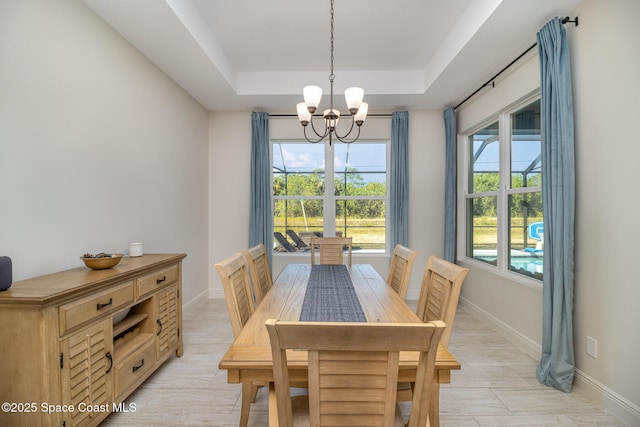 dining space featuring an inviting chandelier, a tray ceiling, and light hardwood / wood-style floors