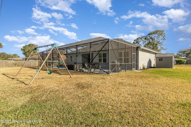 rear view of property with a playground, a lawn, glass enclosure, and a shed