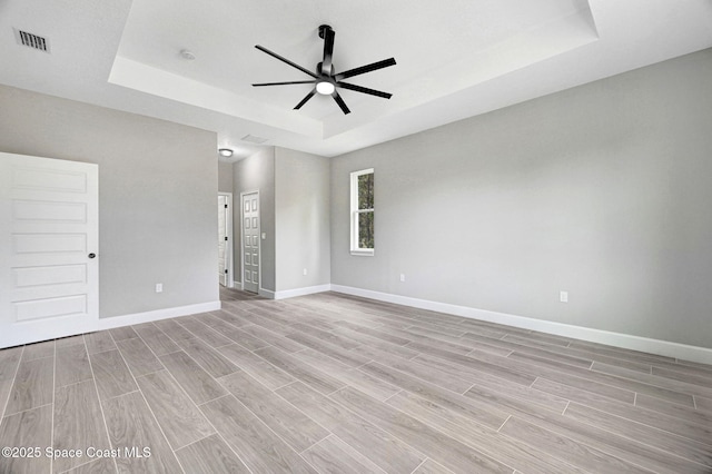 unfurnished room with ceiling fan and a tray ceiling