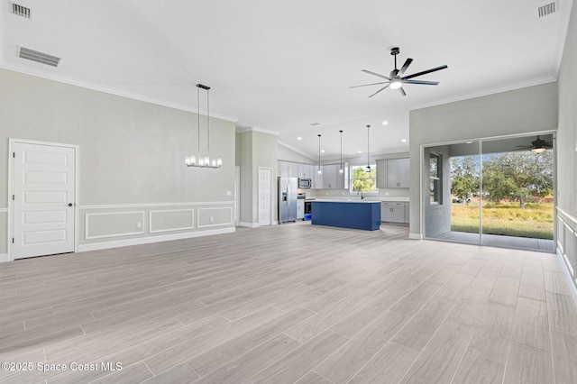 unfurnished living room with ornamental molding, ceiling fan with notable chandelier, and light wood-type flooring