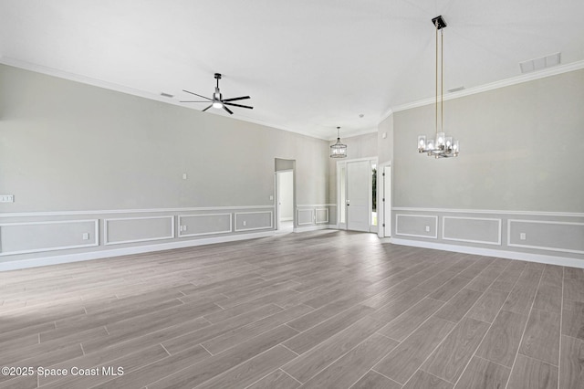 unfurnished living room featuring ceiling fan with notable chandelier, light hardwood / wood-style flooring, and ornamental molding