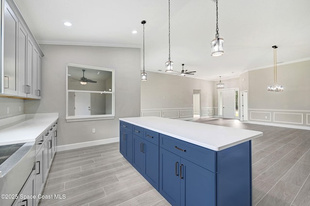 kitchen with ornamental molding, decorative light fixtures, a center island, and ceiling fan with notable chandelier