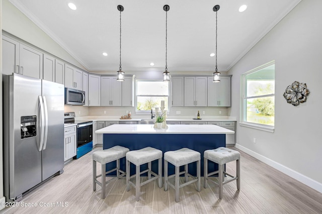 kitchen with vaulted ceiling, light countertops, appliances with stainless steel finishes, and a breakfast bar