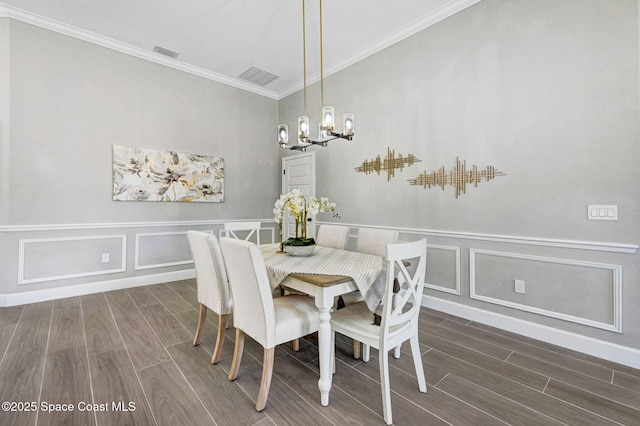 dining space featuring a chandelier, ornamental molding, visible vents, and wood tiled floor