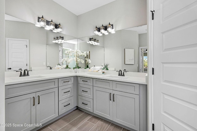 bathroom with wood tiled floor, a sink, and double vanity