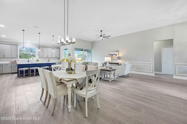 dining area featuring recessed lighting, a decorative wall, a ceiling fan, wainscoting, and wood tiled floor