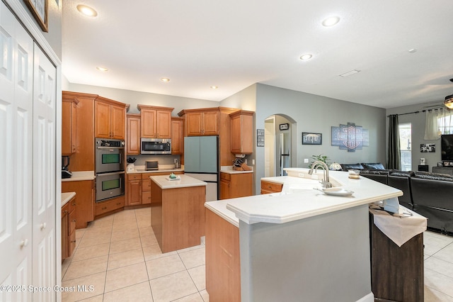 kitchen featuring light tile patterned flooring, stainless steel appliances, sink, and a kitchen island with sink