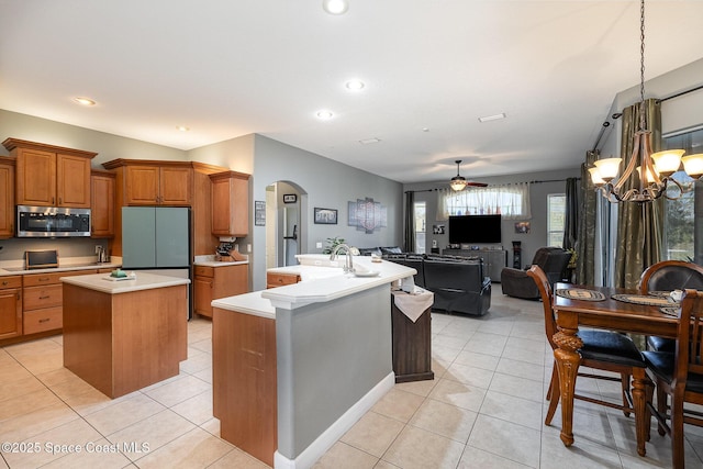 kitchen with refrigerator, light tile patterned floors, a kitchen island, pendant lighting, and ceiling fan with notable chandelier