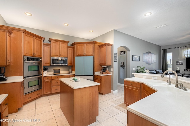 kitchen featuring sink, light tile patterned flooring, stainless steel appliances, and a kitchen island