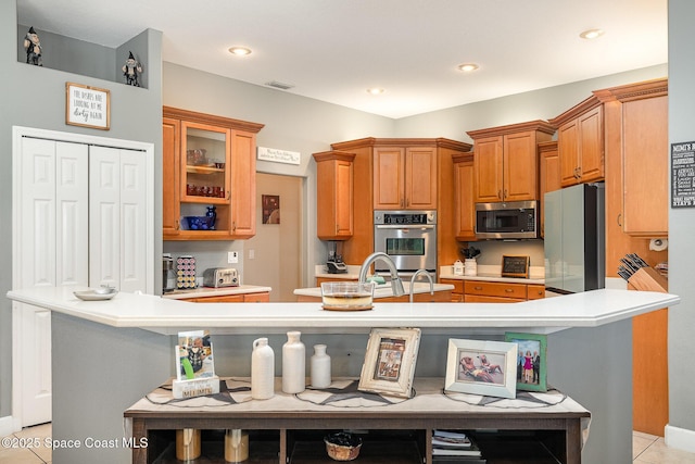 kitchen with appliances with stainless steel finishes, a center island with sink, and a kitchen bar