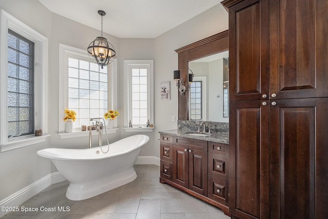 bathroom featuring tile patterned floors, a tub to relax in, a chandelier, and vanity