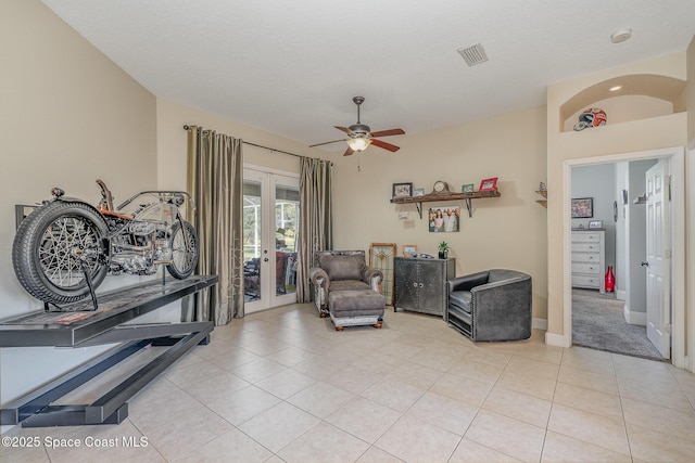 living area with french doors, ceiling fan, light tile patterned flooring, and a textured ceiling