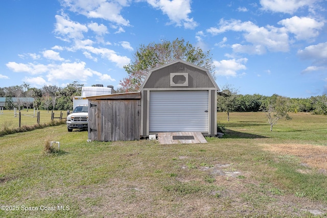 view of outbuilding with a garage, a yard, and a rural view