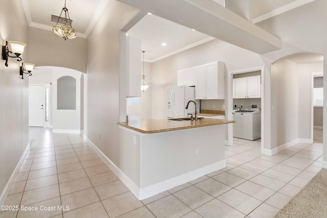 kitchen with washer / dryer, white refrigerator with ice dispenser, white cabinets, and decorative light fixtures