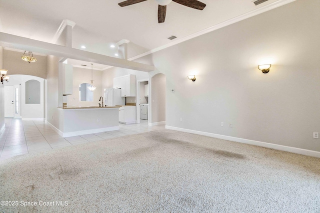 unfurnished living room featuring light tile patterned flooring, ceiling fan with notable chandelier, washer / dryer, sink, and ornamental molding