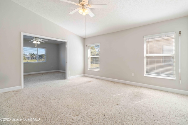 carpeted empty room with a healthy amount of sunlight, ceiling fan, vaulted ceiling, and a textured ceiling