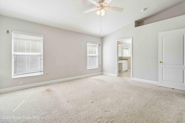 empty room with light carpet, ceiling fan, vaulted ceiling, and a textured ceiling