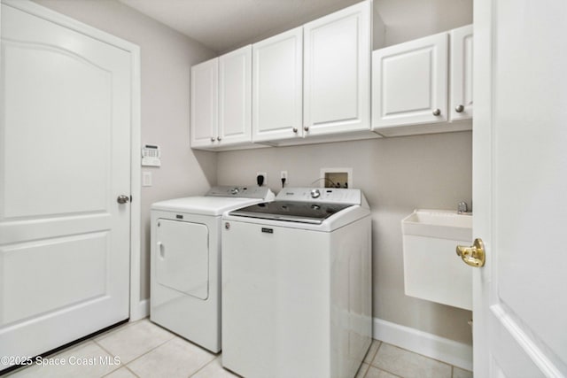 laundry room featuring separate washer and dryer, sink, light tile patterned floors, and cabinets