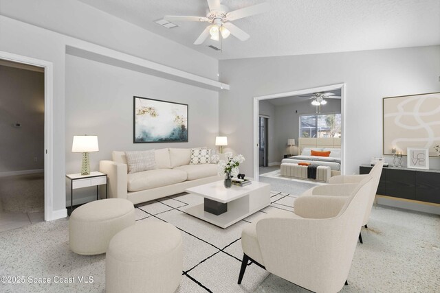 living room featuring ceiling fan, vaulted ceiling, and a textured ceiling