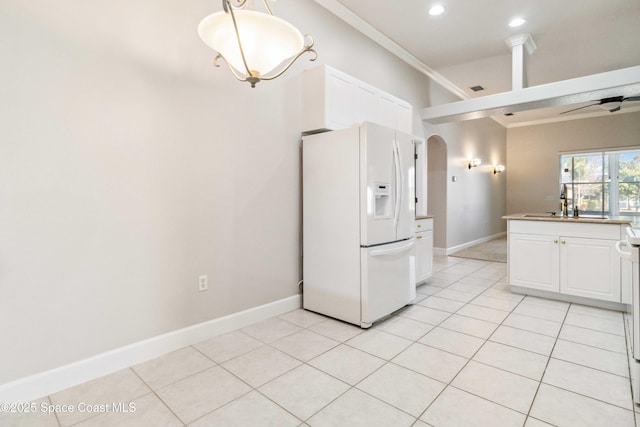 kitchen with light tile patterned floors, sink, white refrigerator with ice dispenser, ornamental molding, and white cabinets