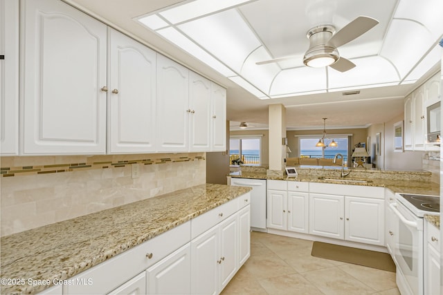 kitchen with white cabinetry, a sink, white appliances, a peninsula, and ceiling fan with notable chandelier