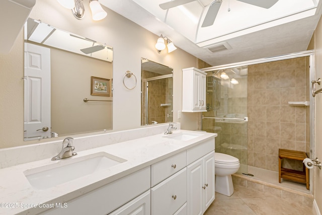 bathroom featuring tile patterned floors, toilet, a shower with shower door, vanity, and ceiling fan