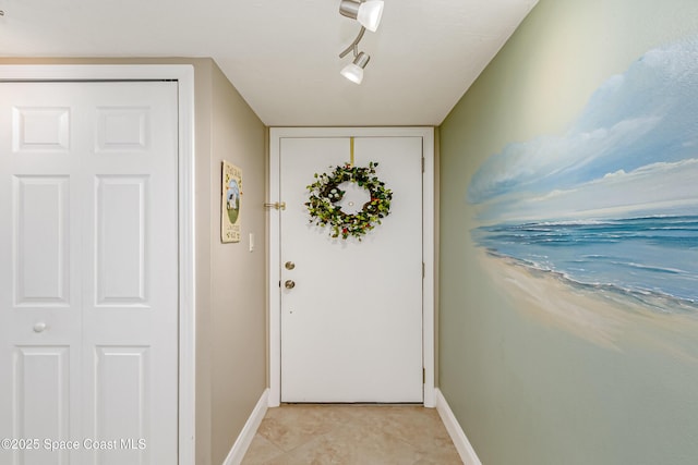 doorway to outside with light tile patterned floors and track lighting