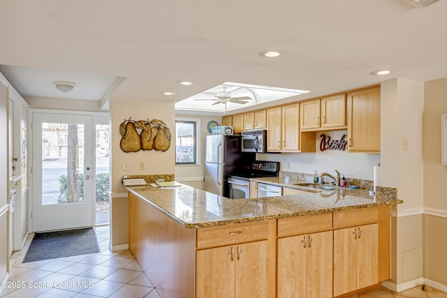 kitchen with stainless steel appliances, sink, light stone counters, and kitchen peninsula