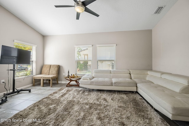 living room featuring light tile patterned flooring, ceiling fan, vaulted ceiling, and a wealth of natural light