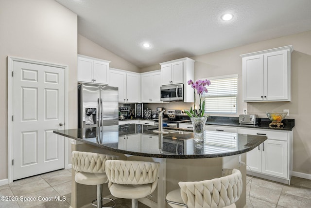 kitchen featuring appliances with stainless steel finishes, a center island with sink, and white cabinets