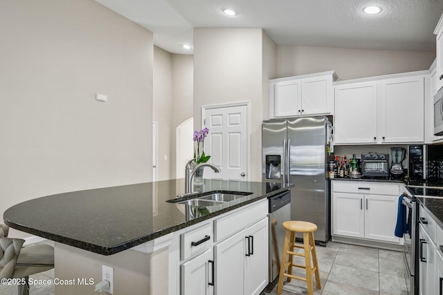 kitchen featuring white cabinetry, sink, dark stone counters, and a center island with sink