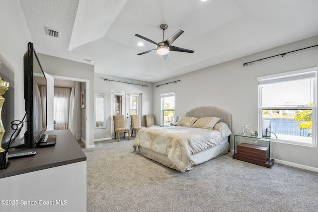 carpeted bedroom with ceiling fan, a textured ceiling, and a tray ceiling