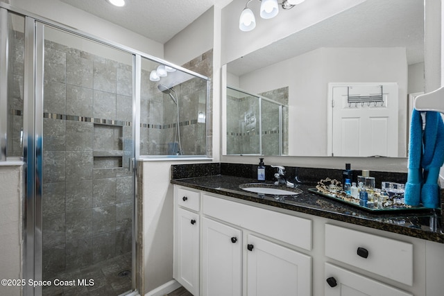 bathroom featuring vanity, an enclosed shower, and a textured ceiling