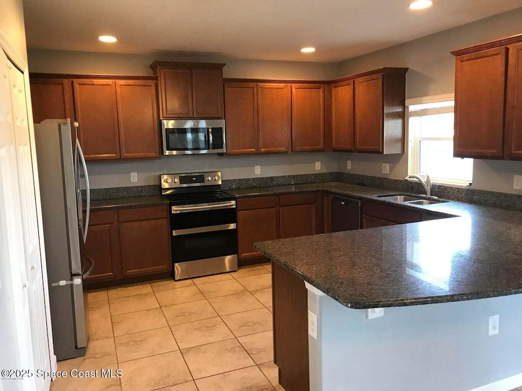 kitchen with stainless steel appliances, kitchen peninsula, sink, and light tile patterned floors