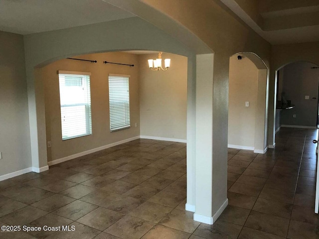 unfurnished room with a notable chandelier and dark tile patterned flooring