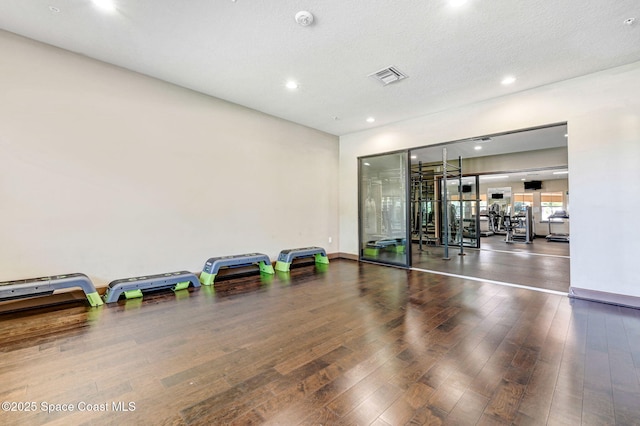 workout room featuring a textured ceiling and dark hardwood / wood-style flooring