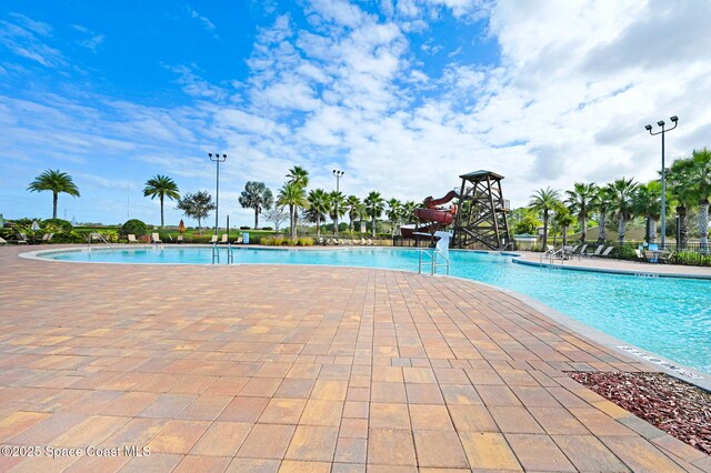 view of swimming pool with a patio and a water slide