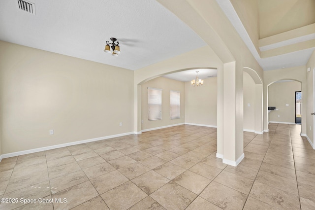 spare room featuring light tile patterned flooring and a notable chandelier